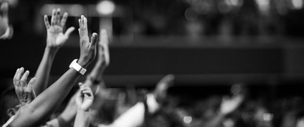 Black and white image of audience with hands raised, capturing concert energy.